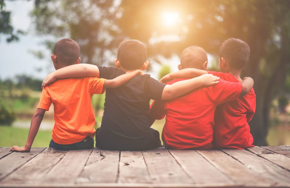 Group of kids friends arm around sitting together
